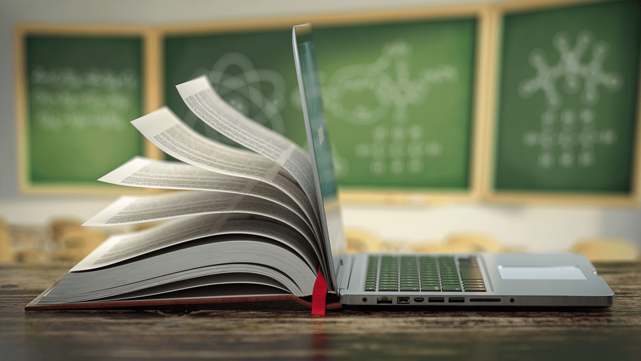 book open against back of laptop with chalkboards in background